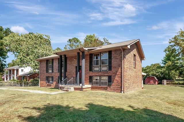 split foyer home featuring brick siding, fence, a shed, an outdoor structure, and a front lawn