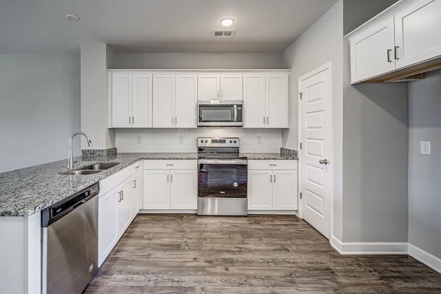 kitchen featuring hardwood / wood-style flooring, sink, backsplash, white cabinetry, and appliances with stainless steel finishes