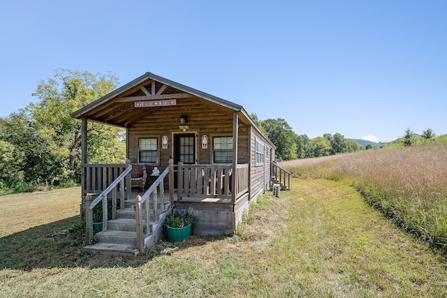 view of front of property with a porch, a rural view, and a front lawn