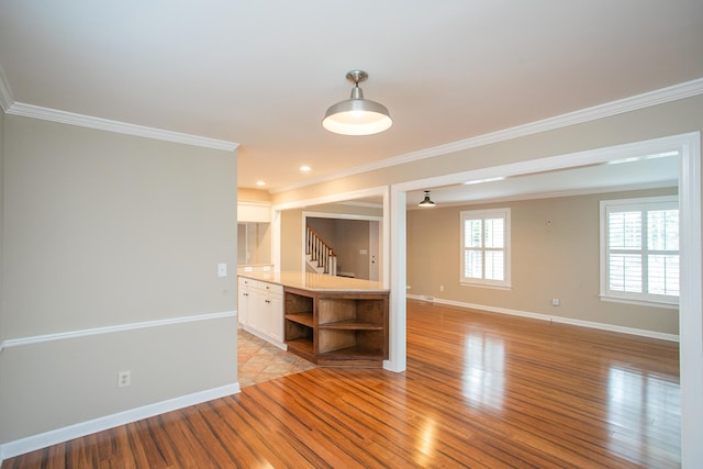 interior space featuring light wood-type flooring, ceiling fan, and crown molding