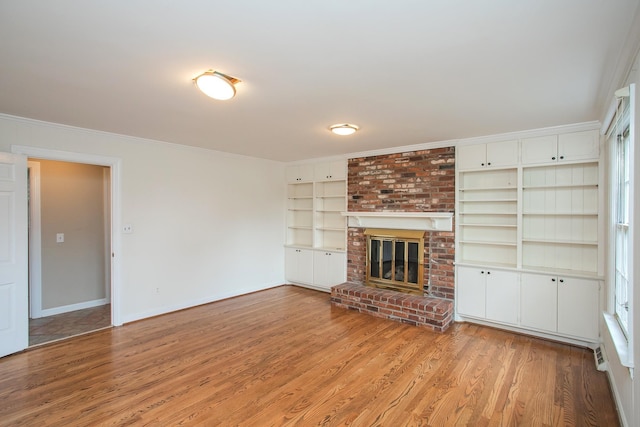 unfurnished living room featuring a brick fireplace, ornamental molding, and light hardwood / wood-style floors