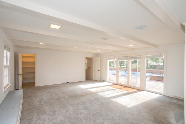 carpeted spare room featuring beamed ceiling