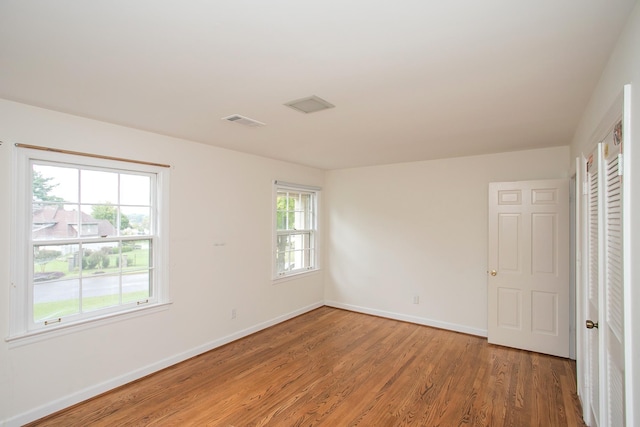 unfurnished bedroom featuring multiple windows and hardwood / wood-style floors