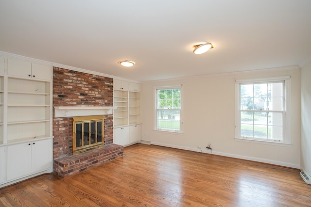 unfurnished living room featuring crown molding, light hardwood / wood-style flooring, and a brick fireplace