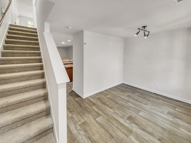 stairs with recessed lighting, wood finished floors, and baseboards