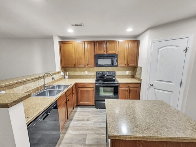 kitchen featuring brown cabinets, visible vents, backsplash, a sink, and black appliances