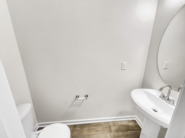 bathroom with a sink, toilet, and baseboards