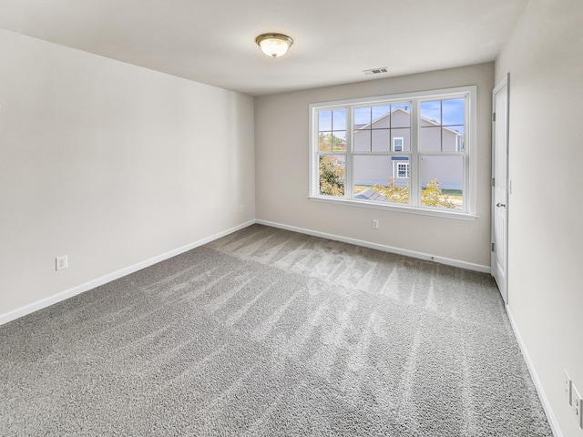 carpeted spare room featuring visible vents and baseboards