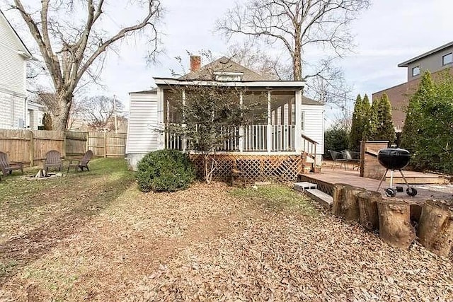 rear view of house featuring a sunroom, fence, and a chimney