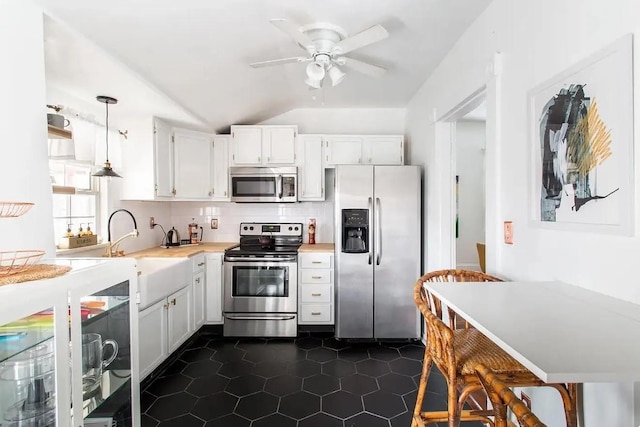 kitchen featuring white cabinets, decorative backsplash, appliances with stainless steel finishes, light countertops, and a sink