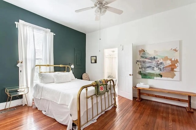 bedroom featuring visible vents, hardwood / wood-style floors, a ceiling fan, electric panel, and baseboards