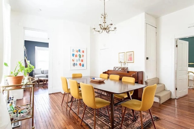 dining area featuring wood-type flooring, a towering ceiling, and an inviting chandelier