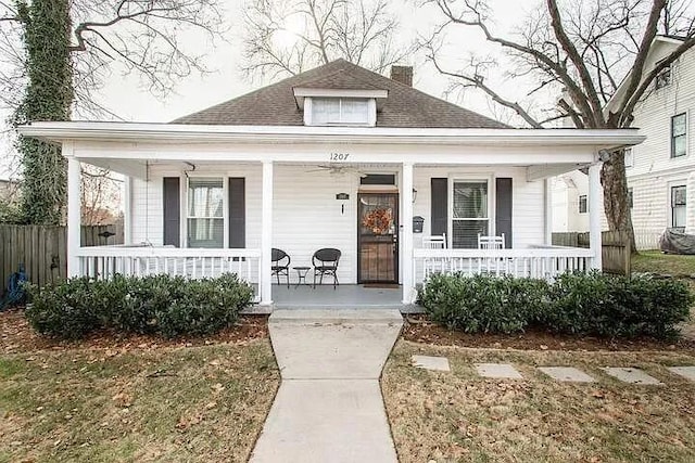 bungalow-style home featuring a porch, fence, and a chimney