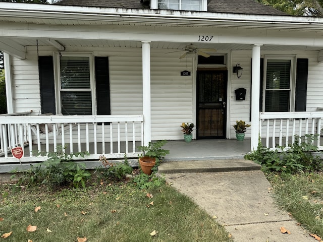 entrance to property with a porch and a shingled roof