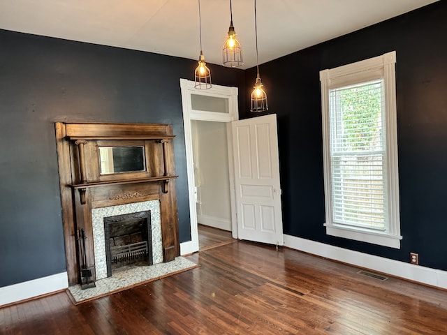 unfurnished living room with visible vents, a fireplace, baseboards, and wood finished floors