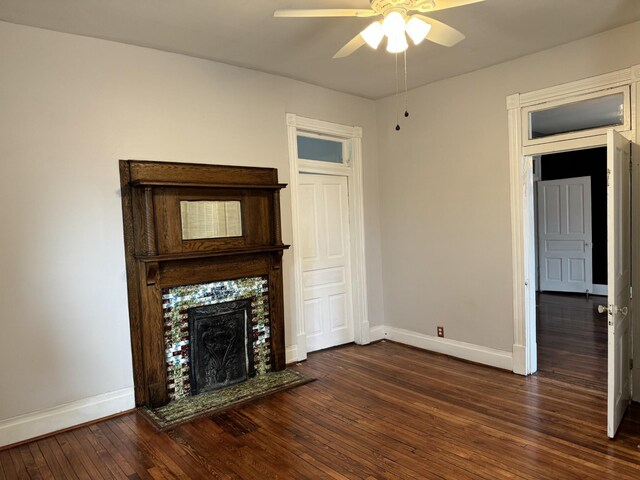 unfurnished living room featuring a ceiling fan, dark wood-style flooring, a fireplace, and baseboards