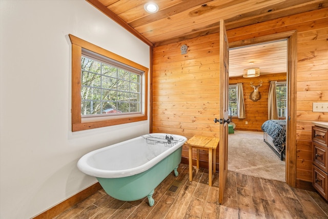 bathroom featuring hardwood / wood-style flooring, wooden ceiling, plenty of natural light, and a washtub