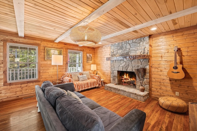 living room with wood ceiling, hardwood / wood-style flooring, beamed ceiling, a fireplace, and wooden walls