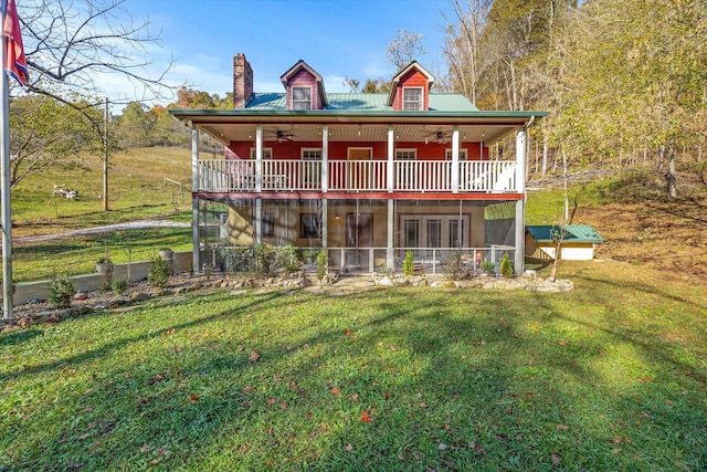 rear view of house with ceiling fan, a lawn, and an outdoor structure