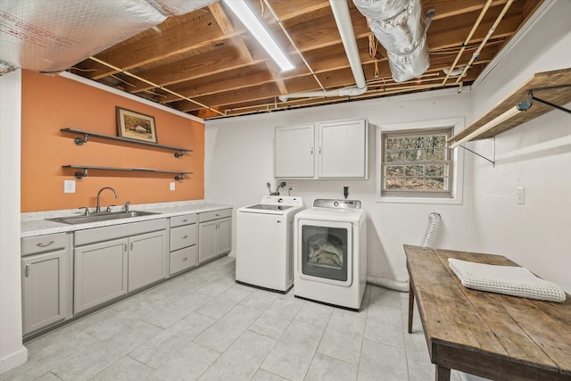 clothes washing area with sink, independent washer and dryer, and cabinets