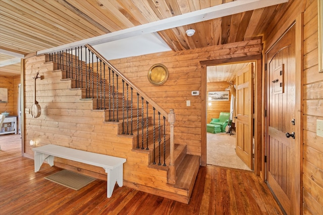 stairs featuring wood ceiling, hardwood / wood-style floors, and wooden walls