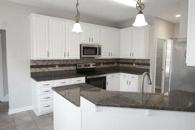 kitchen with pendant lighting, stainless steel appliances, tasteful backsplash, and white cabinetry