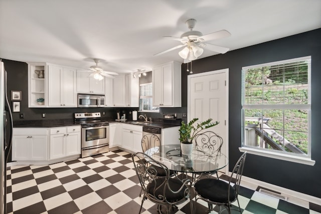 kitchen with a healthy amount of sunlight, appliances with stainless steel finishes, white cabinets, and ceiling fan