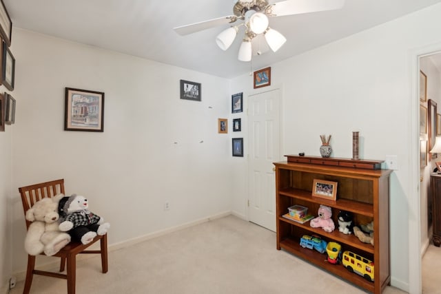 living area featuring light carpet and ceiling fan