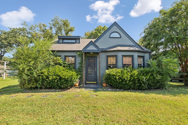 view of front facade with a shingled roof, a front yard, and stucco siding