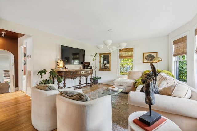 living area with a chandelier, arched walkways, visible vents, and wood finished floors