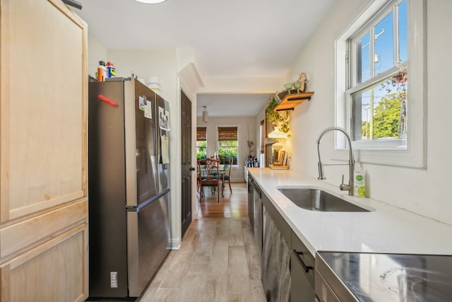 kitchen with light hardwood / wood-style floors, stainless steel refrigerator, sink, light brown cabinets, and a wealth of natural light