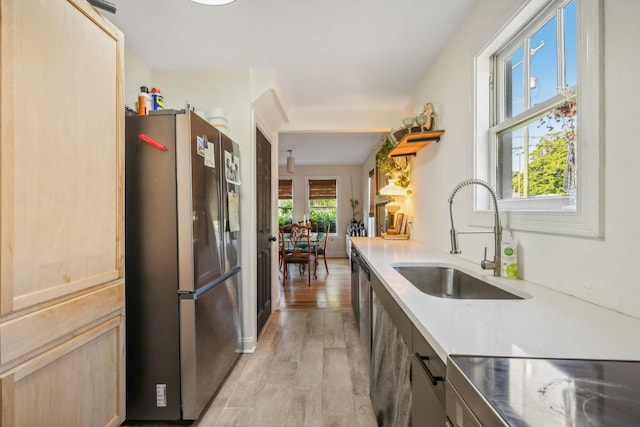 kitchen with a sink, light countertops, light wood-type flooring, stainless steel refrigerator with ice dispenser, and light brown cabinetry