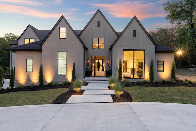 view of front facade featuring a front lawn, roof with shingles, and stucco siding