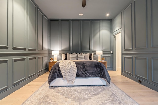 bedroom featuring recessed lighting, wood finished floors, and a decorative wall