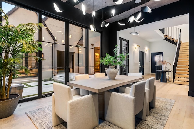 dining space featuring a high ceiling, stairway, and wood finished floors