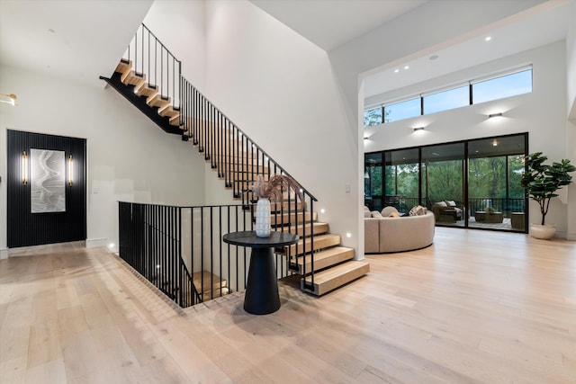 staircase featuring a high ceiling, wood finished floors, and baseboards