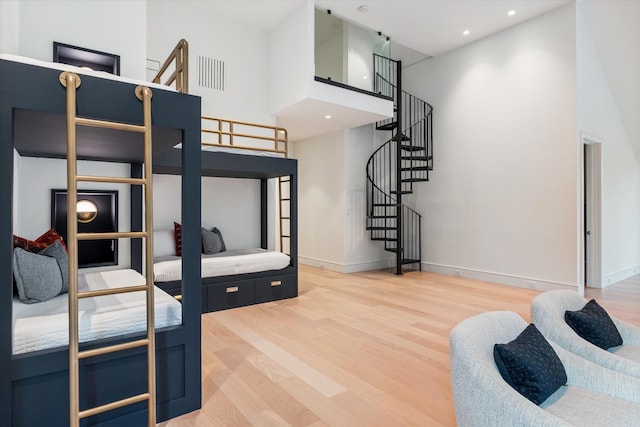 bedroom with baseboards, visible vents, a towering ceiling, wood finished floors, and recessed lighting