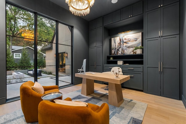 office area with a healthy amount of sunlight, light wood finished floors, and an inviting chandelier