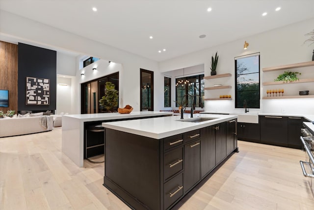 kitchen with light countertops, a center island with sink, and open shelves