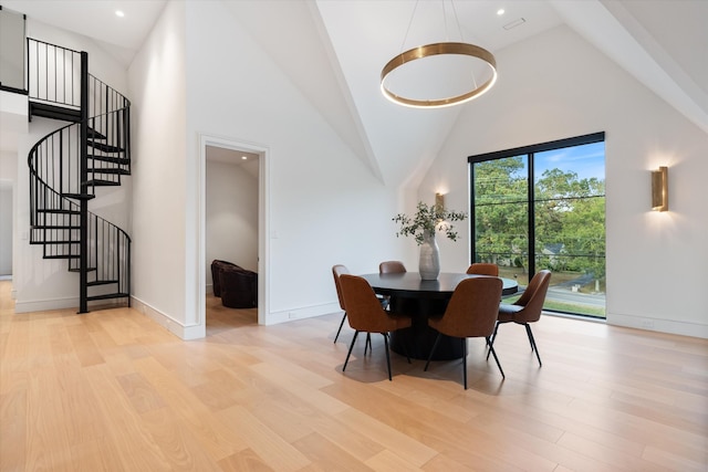 dining space with light wood finished floors, recessed lighting, high vaulted ceiling, baseboards, and stairs