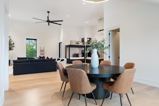 dining area featuring light wood-type flooring, ceiling fan, a high ceiling, and recessed lighting