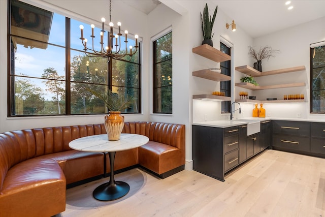 bar with pendant lighting, a sink, and light wood finished floors