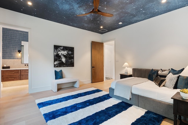 bedroom featuring baseboards, visible vents, ensuite bath, and light wood finished floors