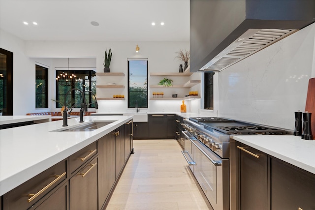 kitchen with wall chimney exhaust hood, light countertops, double oven range, open shelves, and a sink