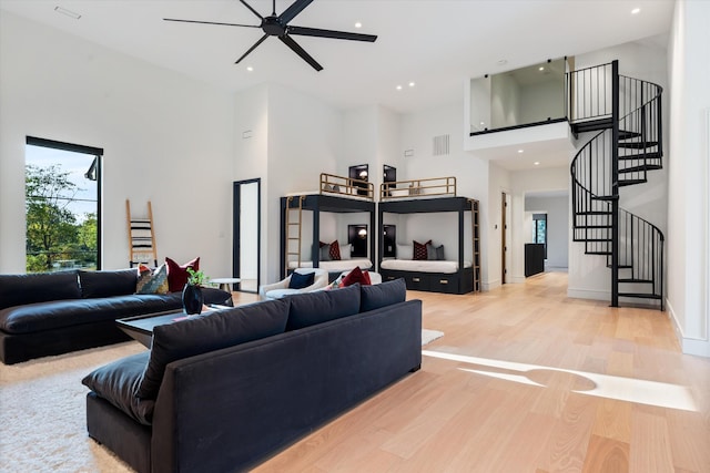 living area featuring recessed lighting, a high ceiling, visible vents, stairs, and light wood finished floors