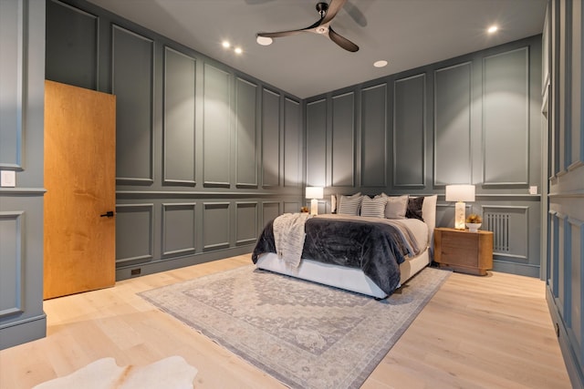 bedroom with light wood-style flooring, a decorative wall, a ceiling fan, and recessed lighting