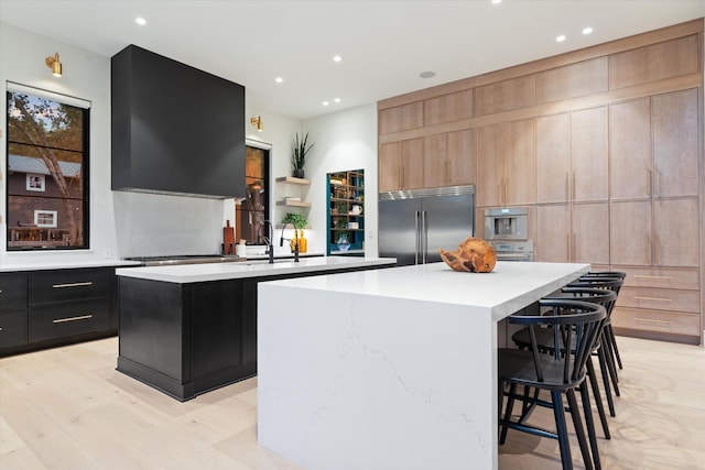 kitchen with stainless steel appliances, modern cabinets, light countertops, and a kitchen island with sink