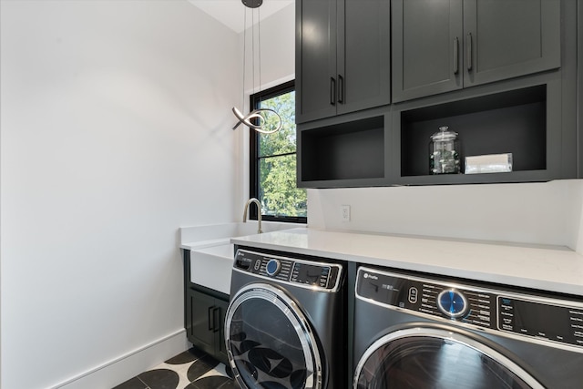 washroom with cabinet space, baseboards, a sink, and washing machine and clothes dryer