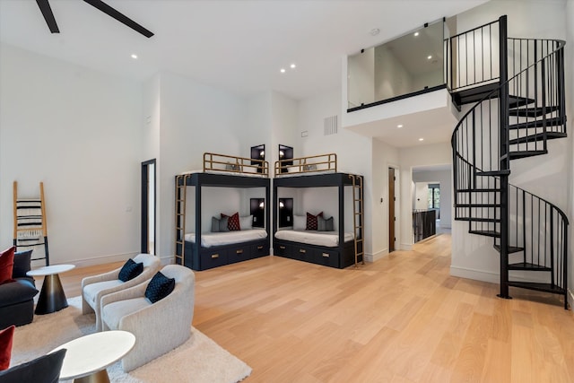 living room with stairs, visible vents, a towering ceiling, and wood finished floors