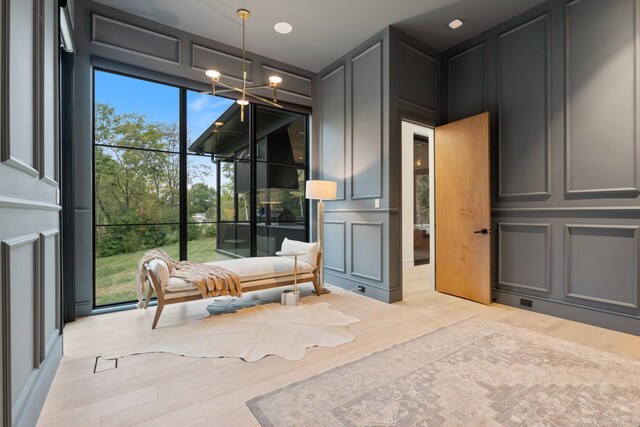 interior space featuring an inviting chandelier, light wood-style flooring, and a decorative wall